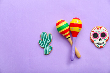 Mexican maracas with cookies on lilac background