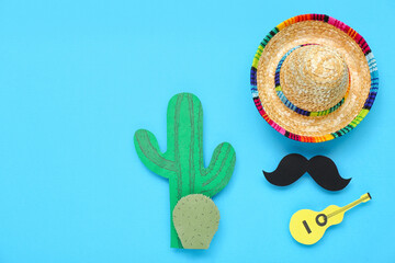 Sombrero hat with paper mustache, guitar and cactus on blue background