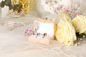 Box with wedding rings and flowers on white table, closeup