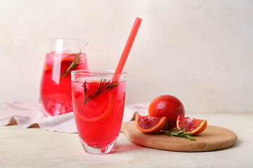 Glass of tasty blood orange lemonade on light background