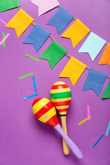 Mexican maracas with paper flags and confetti on purple background