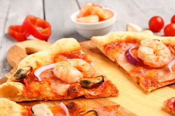 Board of tasty seafood pizza on light wooden background, closeup