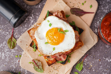 Delicious sandwich with fried egg and bacon on grey background