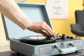 Woman using record player at home, closeup