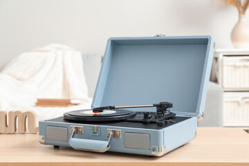 Record player with vinyl disk on table in room