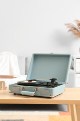 Record player with vinyl disk on table in room