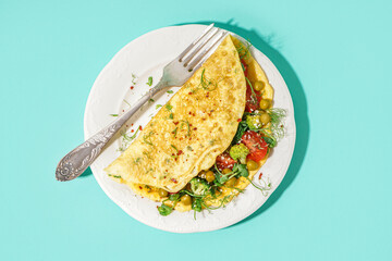 Tasty omelet with vegetables on blue background