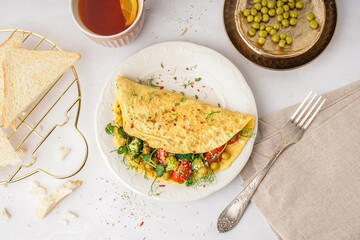 Tasty omelet with vegetables on light background