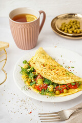 Tasty omelet with vegetables on light background