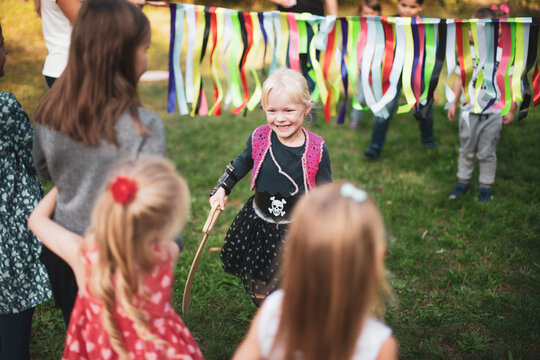 Little girl in a pirate costume with a wooden saber on a holiday - Powered by Adobe