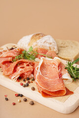 Wooden board with slices of tasty jamon on beige background, closeup