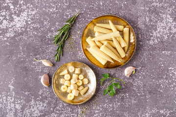 Plates with cut and whole canned baby corn cobs on grey grunge background