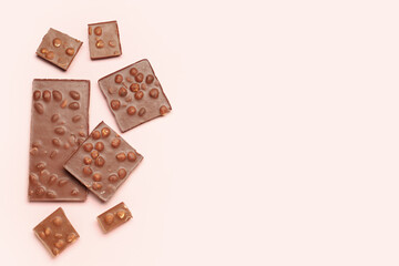 Sweet tasty chocolate with nuts on  light pink background