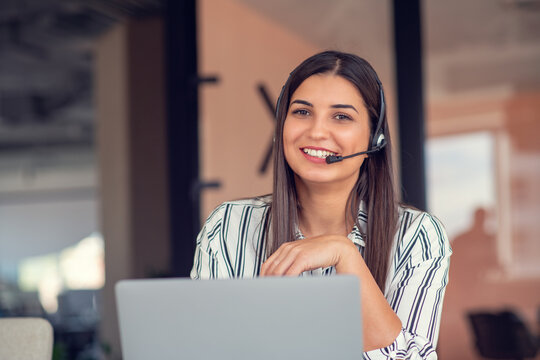 Young friendly operator woman agent with headsets working in a call centre.