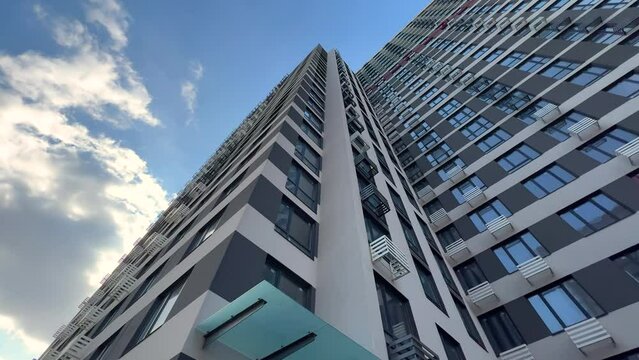 The exterior of a recently built modern high-rise apartment building with air conditioning baskets on the facade. View from bottom to top. Extreme wide angle shot