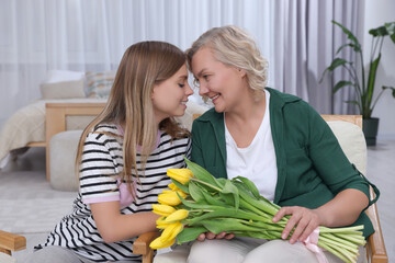 Young daughter congratulating her mom with flowers at home. Happy Mother's Day