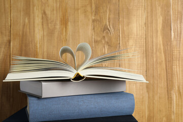 Stack of hardcover books on wooden background, space for text