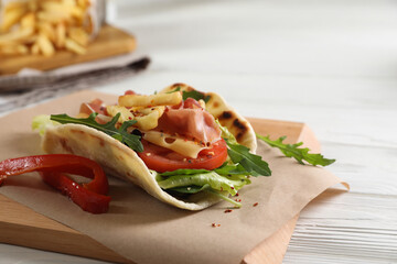 Delicious pita wrap with jamon, vegetables and greens on wooden table