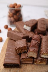 Pieces of different tasty chocolate bars on wooden board, closeup