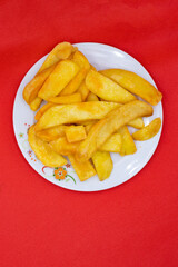 A plate of french fries on a red background.