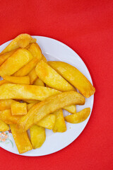 A plate of french fries on a red background.