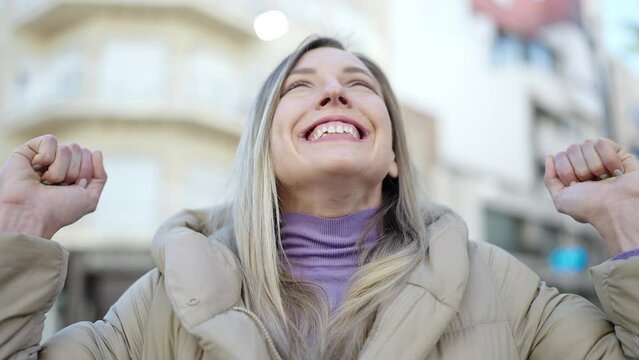 Young blonde woman smiling confident with winner expression at street