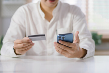 Cropped shot of millennial man is paying with a credit card online while placing orders via mobile internet and making transactions using a mobile banking application.