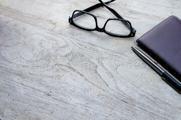 Blank wooden table with eyeglasses, pen, and notebook. Copy space for messages and text 