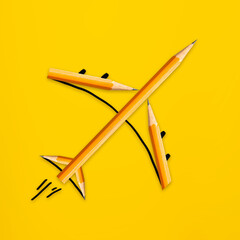 Airplane made from wooden pencils on yellow background, creative concept artwork