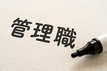 管理職と書かれたノートとマーカー