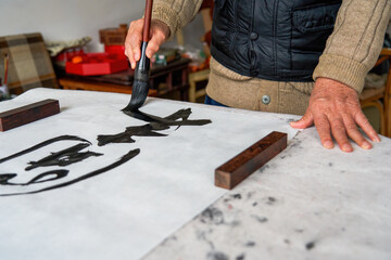 An old Chinese calligrapher is creating and writing calligraphy works.
Translation: carry on the past and open up the future.