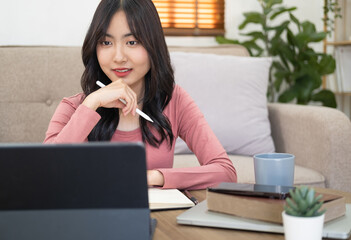 Asian woman  in online learning ,  watching educational webinar on laptop. Young businesswoman holding video call with clients partners.Young female student study in home.