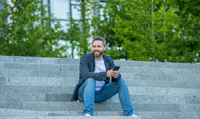 Obraz premium happy man messaging on phone outside. photo of man messaging on phone in hands.