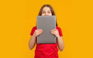 happy girl behind laptop on yellow background