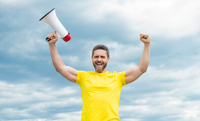 man in yellow shirt holding megaphone on sky background