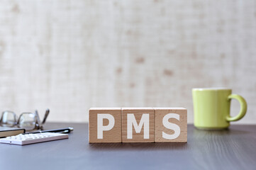 There is wood cube with the word PMS. It is an acronym for Personal information protection management systems an eye-catching image.