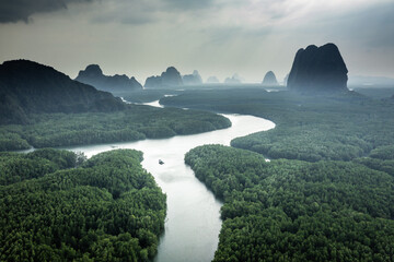 River and green forest in Thailand natural park, aerial view.  Beautiful natural scenery of river in southeast Asia tropical green forest with mountains in background, aerial view drone shot. © Jitti