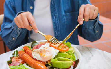 Closeup image of a woman eating salad and drinking coffee in cafe