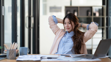 Calm smiling businesswoman relaxing in a comfortable office chair hands behind her head, happy...