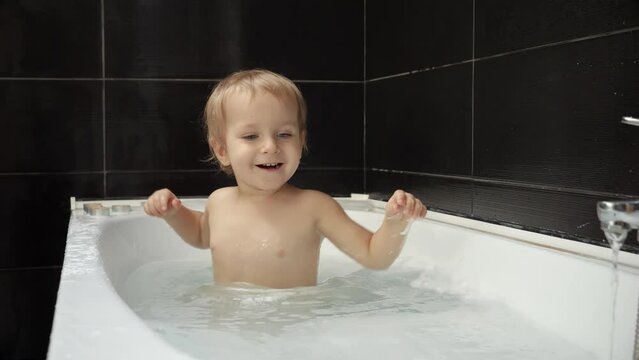Smiling baby boy having a fun time in the bath with water and foam. Developing good hygiene practices and creating a playful environment for babies