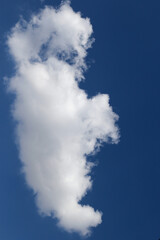Cloud with a ghostly shape floats high in the blue sky