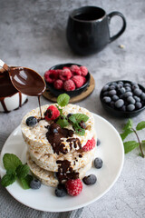 Rice cakes with berries and chocolate. Deliciously. A snack On a gray background