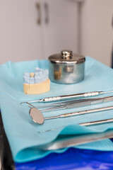 a tray of dental instruments is featured in the foreground with a ceramic dental crown in the background in a dental office