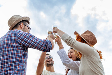 Group of four friends cheers with glases full of wine and feel so happy