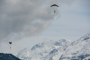 View on snow covered mountains in the Swiss alps with two paraglider approach landing