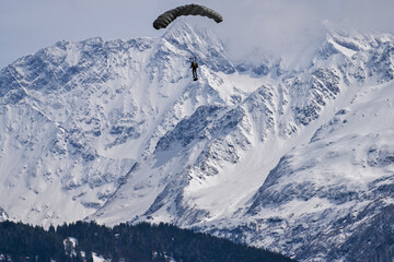 Army paraglider in the swiss Alps - snow covered mountains, lonely paraglider
