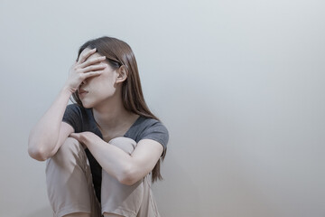 Naklejka premium Female having depression sitting alone hands covering face bedroom corner. woman headache unhappy emotion. young anxiety despairing mental health problems.