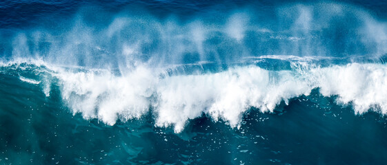 Elevated panoramic view captures the sheer power and strength of a massive breaking wave, as it...