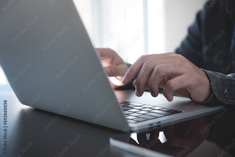 Wall mural man hands typing on laptop computer keyboard and surfing the internet on office table, online workin