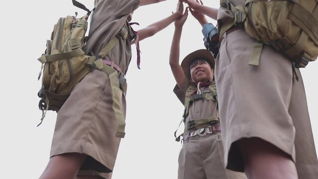  Asian Three Scouts rejoice at rock climbing success in the evening at sunset.